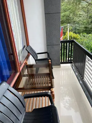 two chairs sitting on the balcony of a house at Dakshinakasi Guest House in Thirunelli