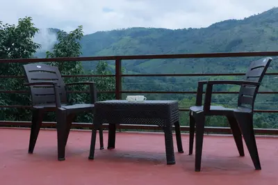 two chairs and a table on a balcony with a view at Biosphere in Coonoor