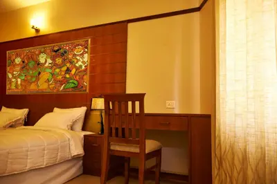 a bedroom with a bed and a desk with a chair at Srivar Hotels in Guruvāyūr