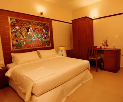 a bedroom with a bed and a painting on the wall at Srivar Hotels in Guruvāyūr