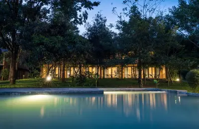 a building with a pond in front of it at night at Klov Resort & Spa in Wayanad
