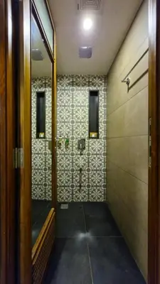 a bathroom with a shower with a tile wall at Klov Resort & Spa in Wayanad