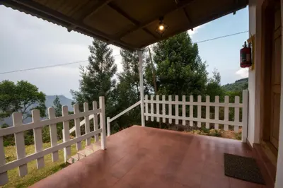 a white fence on a porch with a view at Tranqville Resorts in Ooty