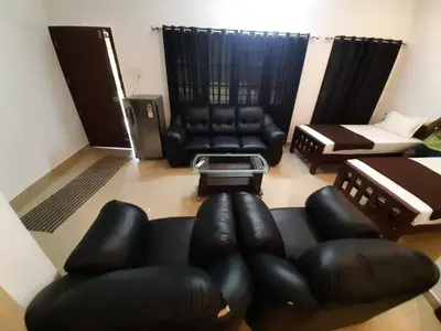 a living room with leather chairs and a couch at 3 Hills Hostel in Wayanad