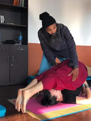 a woman standing on top of a man on a mat at 3 Hills Hostel in Wayanad