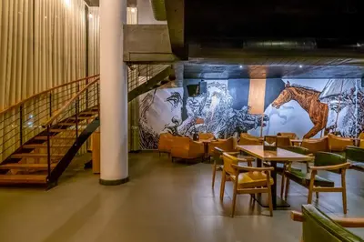a restaurant with tables and chairs and a mural at Samasth Palatial in Mysore