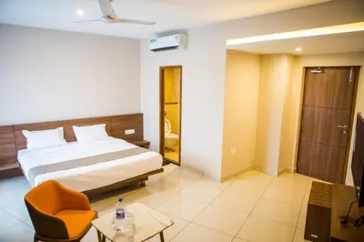 a bedroom with a bed and a chair and a table at Samasth Palatial in Mysore
