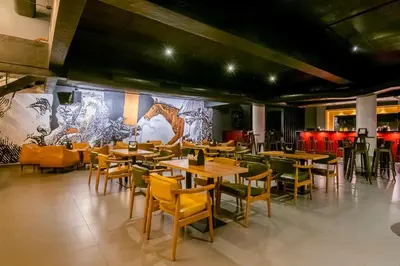 a restaurant with wooden tables and chairs and a mural at Samasth Palatial in Mysore