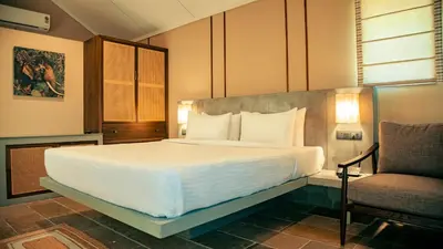 a bedroom with a large white bed and a chair at Fireflies Kabini in Begūr