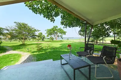 a porch with two chairs and a table with flowers on it at Fireflies Kabini in Begūr