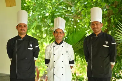 three chefs standing next to each other wearing chef hats at Fireflies Kabini in Begūr