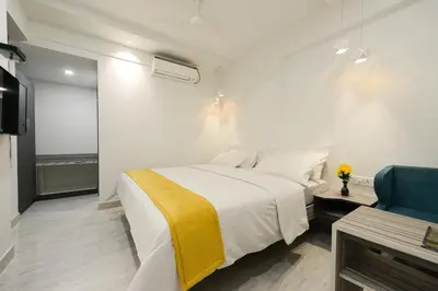 a bedroom with a white bed and a blue chair at Hotel Vijay Fablis in Coimbatore