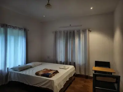 a bedroom with a bed and a window with curtains at H Villa in Nilambūr