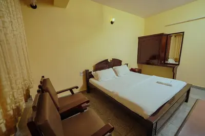 a bedroom with a bed and a chair in it at Hotel oneiro in Trichūr