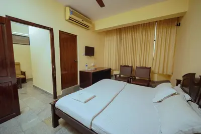 a bedroom with a bed and a desk and chairs at Hotel oneiro in Trichūr