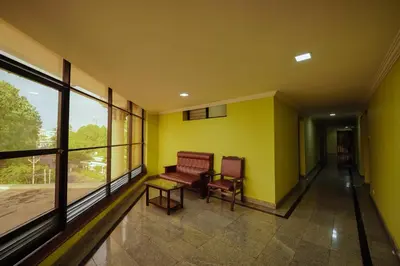 a hallway with a bench and a table and windows at Hotel oneiro in Trichūr