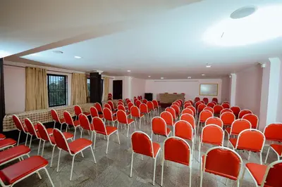 an empty room with red chairs and a wall at Hotel oneiro in Trichūr