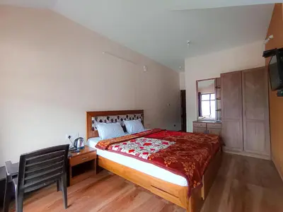 a bedroom with a bed and a desk and a window at Karpagam Residency in Ooty