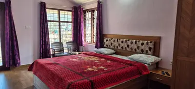 a bedroom with a bed with a red comforter at Karpagam Residency in Ooty