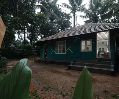 a small green house in the middle of a yard at Babu's Homestay By Lexstays in Mananthavady