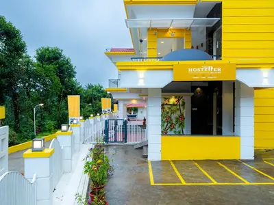 a yellow and white building with a restaurant at The Hosteller Coorg, Madikeri in Madikeri