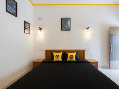 a bedroom with a black bed with two yellow pillows at The Hosteller Coorg, Madikeri in Madikeri