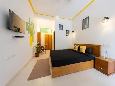 a bedroom with a bed and a tv on a wall at The Hosteller Coorg, Madikeri in Madikeri