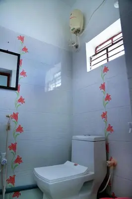 a bathroom with a toilet and flowers on the wall at WHITE HOUSE - 3BHK Elite Apartment in Coimbatore