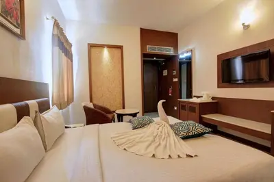 a hotel room with a bed with a swan on it at Hotel Prince Gardens in Coimbatore