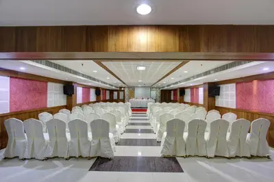 a conference room with white chairs and a table at Hotel Prince Gardens in Coimbatore