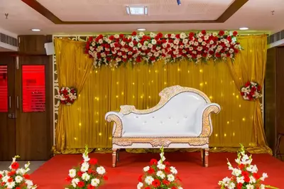 a white couch in front of a stage with flowers at Hotel Prince Gardens in Coimbatore