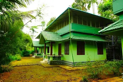 a green house with a green roof at Shibi's Tea Garden Heritage in Vayittiri