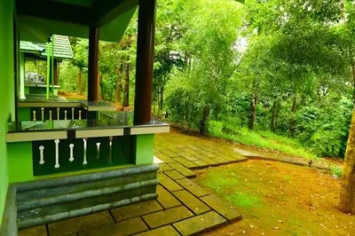 a green house with a porch and a yard at Shibi's Tea Garden Heritage in Vayittiri
