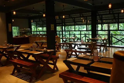 a restaurant with wooden tables and chairs and windows at Vajra Ayurveda and Yoga Retreat in Cochin