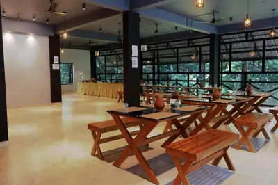 a restaurant with wooden tables and benches and windows at Vajra Ayurveda and Yoga Retreat in Cochin