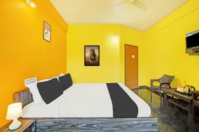 a yellow bedroom with a bed and a desk at Super Collection O Coorg in Madikeri