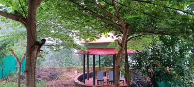 a gazebo with a red roof in the trees at Pauls Retreat Wayanad , Family Resort in Wayanad
