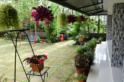 a patio with potted plants and a bench with flowers at Pauls Retreat Wayanad , Family Resort in Wayanad