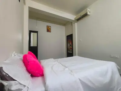 a white bed with a pink pillow on top of it at Jinnens Tourist Home in Ponnāni