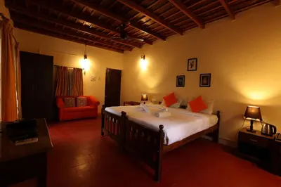 a bedroom with a large bed and a red chair at Avadale Coorg - Stag Groups Not Allowed in Ammatti