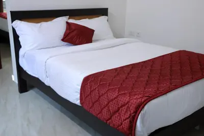 a bed with a red blanket and white pillows at NIDHI RESIDENCY in Guruvāyūr