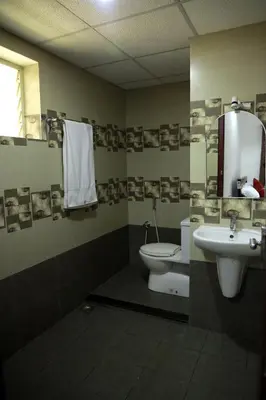 a bathroom with a sink and a toilet and a mirror at NIDHI RESIDENCY in Guruvāyūr