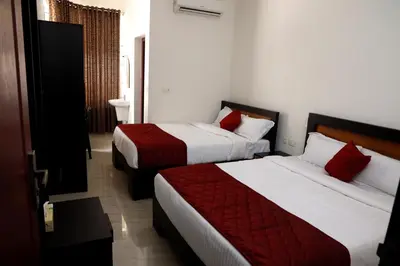 a hotel room with two beds with red pillows at NIDHI RESIDENCY in Guruvāyūr