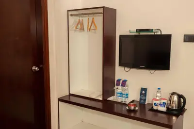 a room with a mirror and a tv on a wall at THE PEBBLE Boutique Hotel in Tiruppūr