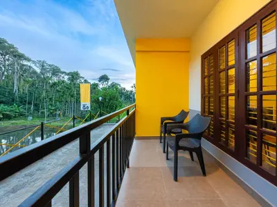 a balcony with chairs and a view of the forest at The Hosteller Coorg Rainforest, Madikeri in Madikeri