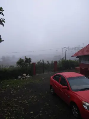 a red car parked in front of a house at Chilly Coorg in Virajpet