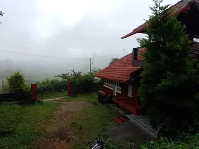 a red house with a tree in front of it at Chilly Coorg in Virajpet