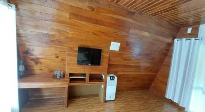 a room with a wooden wall with a desk and a tv at Misty Morning Resorts Wayanad in Ambalavayal