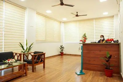 a woman is sitting at a desk in a room with windows at Misty Range Resorts , Marayoor in Marayoor