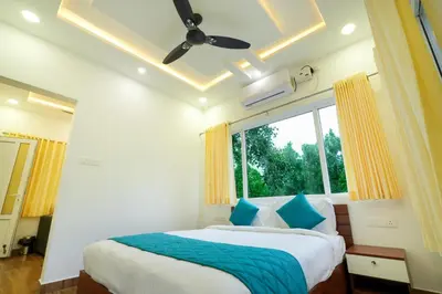 a bedroom with a bed with blue pillows and a window at Misty Range Resorts , Marayoor in Marayoor